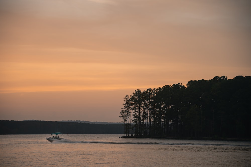 a boat traveling across a body of water at sunset