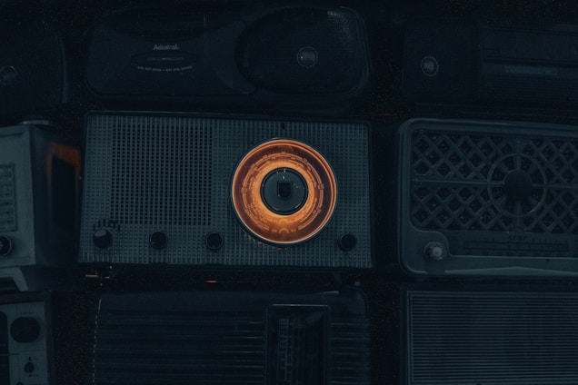 A cozy shelf filled with carefully restored vintage transistor and tube radios glowing softly in warm light.