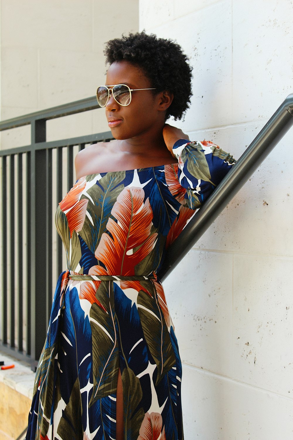 a woman in a floral dress leaning against a wall