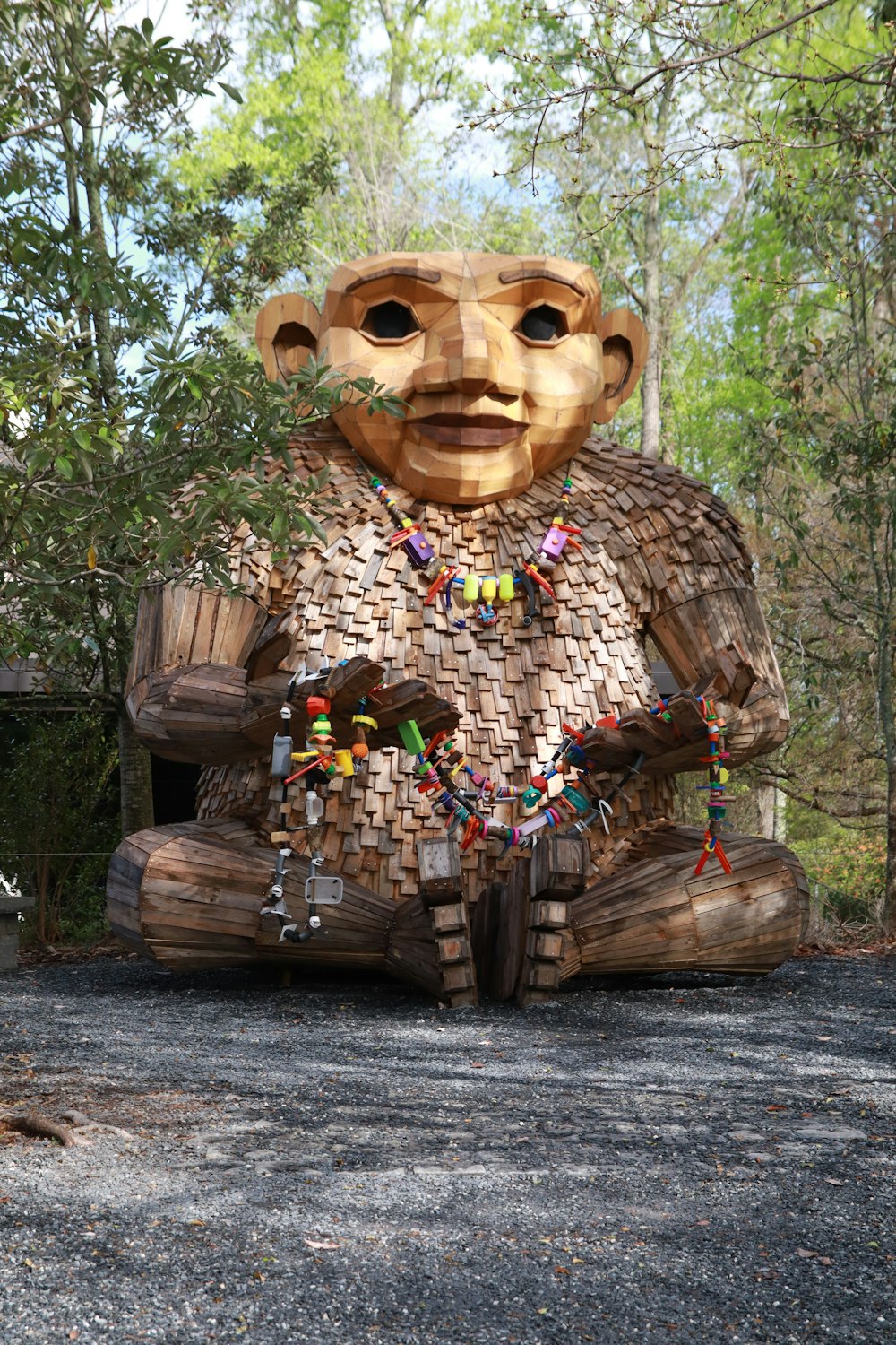 a wooden statue of a man sitting in the middle of a forest