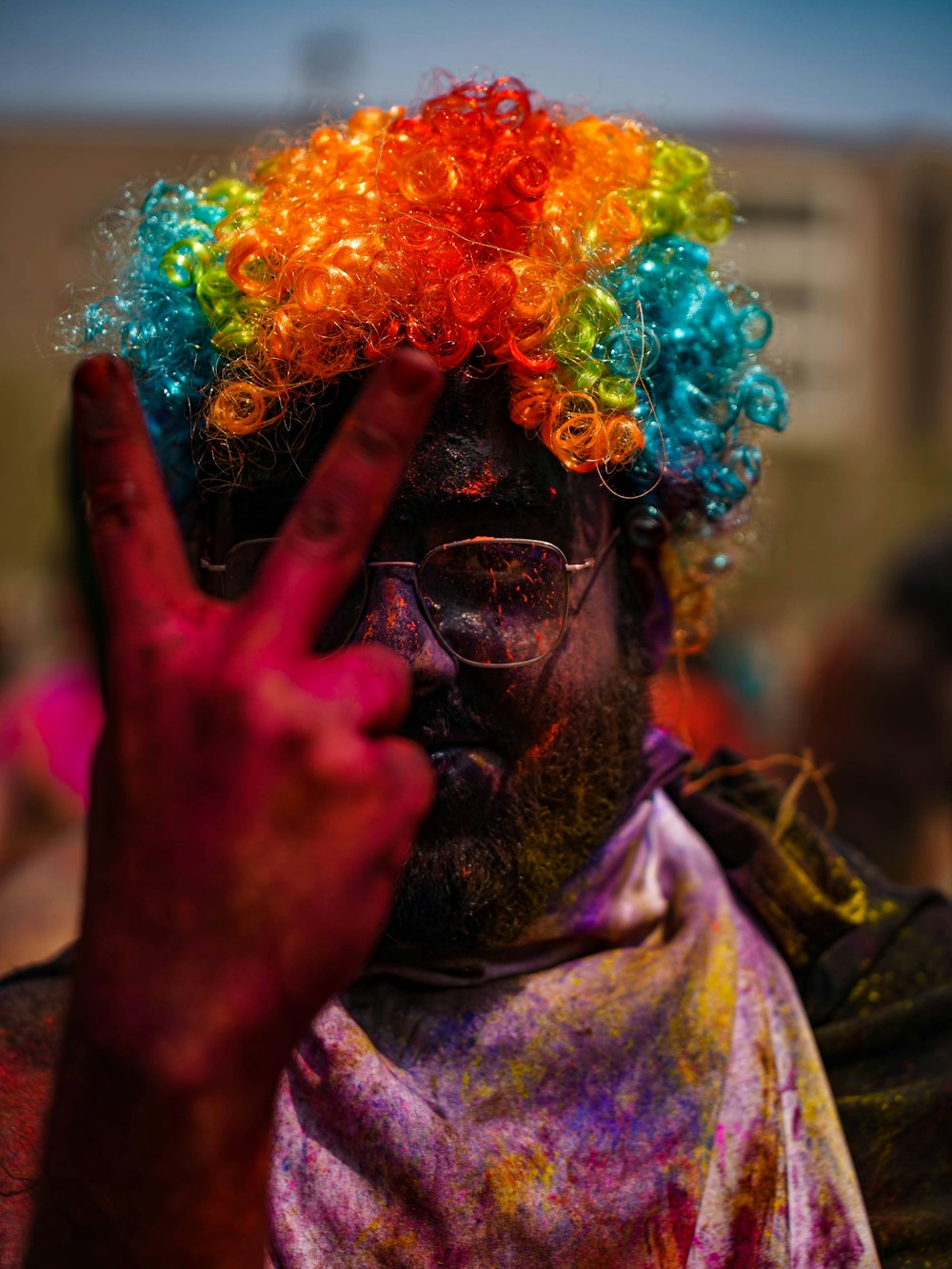 a man with a multicolored wig making a peace sign