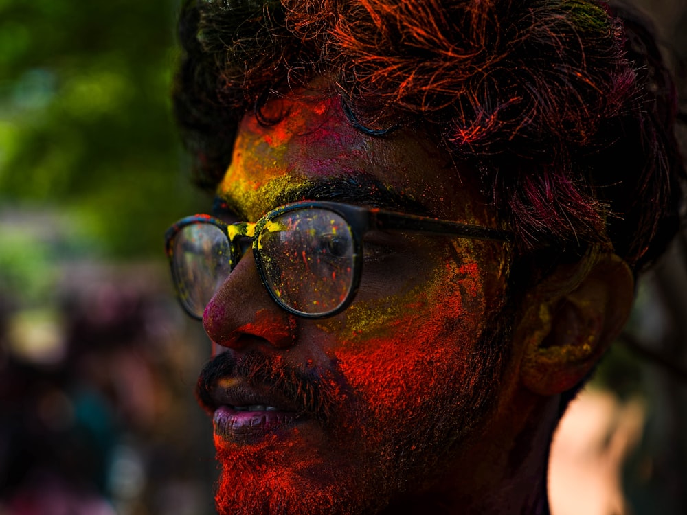 a man with a beard and glasses covered in colored powder