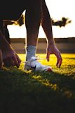Athlete tying laces on sleek soccer cleats before practice on a sunny field