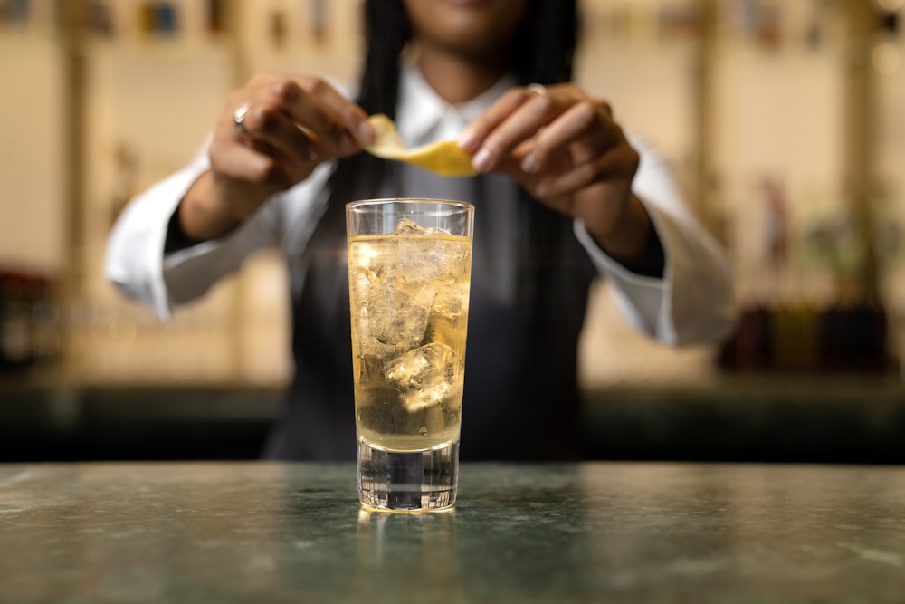 a woman is holding a spoon over a glass of lemonade