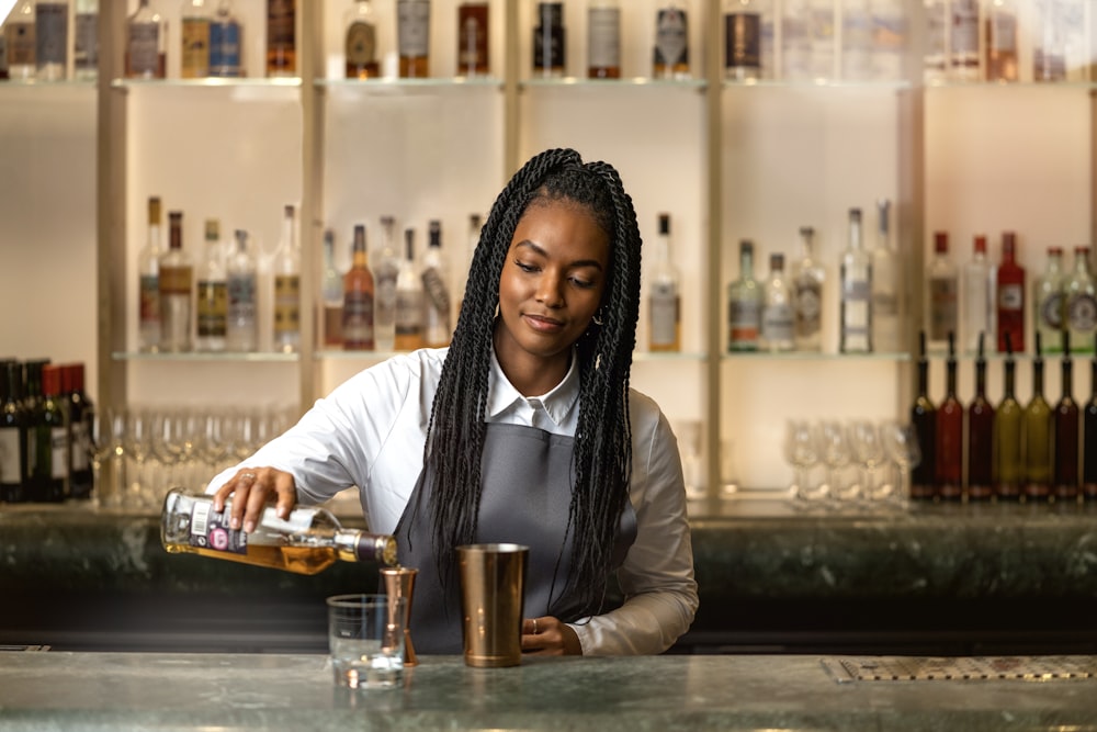 a woman pouring a drink at a bar