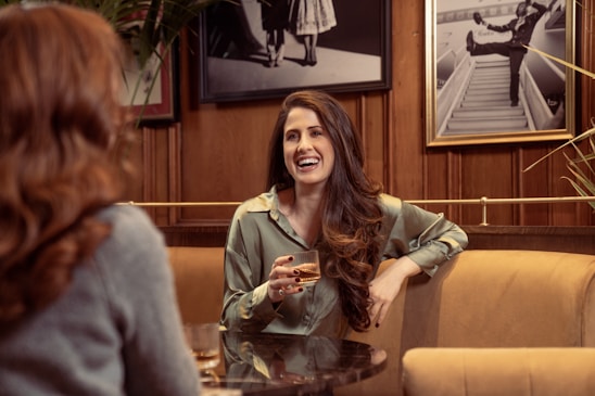 Two people smiling and talking over coffee in a cozy café setting.