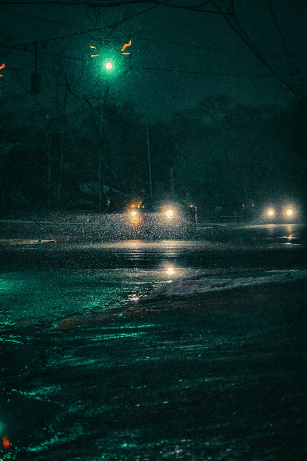 Un semáforo verde colgando sobre una calle mojada