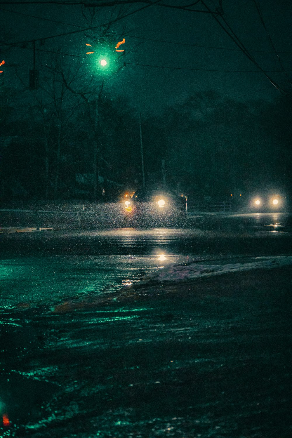 a green traffic light hanging over a wet street