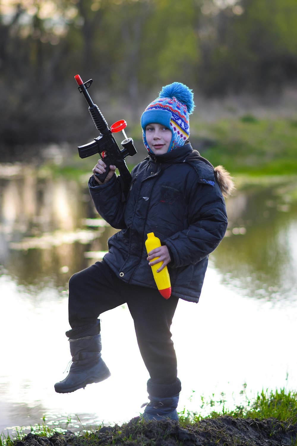 a young boy is holding a toy gun