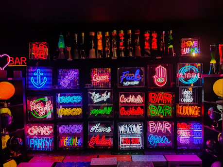 A vibrant neon-lit collage of pop culture icons and symbols representing music, movies, and gaming.