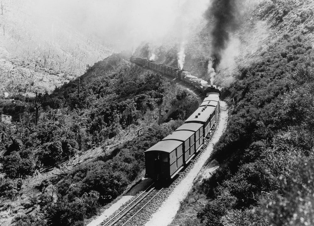 a black and white photo of a train going down the tracks