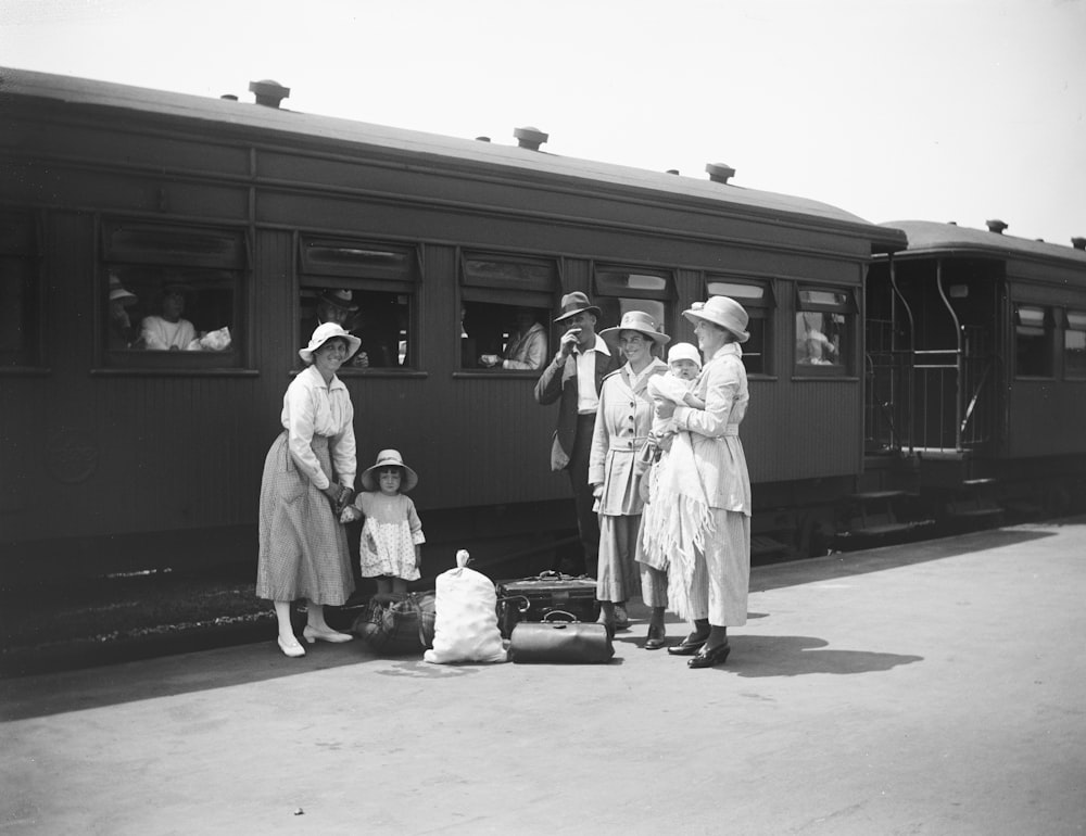 a group of people standing next to a train