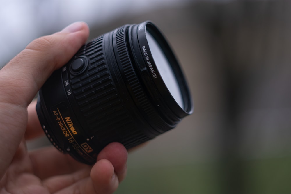 a person holding a camera lens in their hand