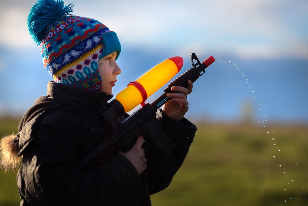 a young boy is holding a toy gun