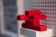 Red LEGO bricks are stacked in an abstract shape against a background of a LEGO baseplate.