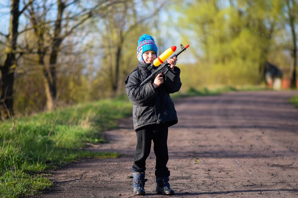 Un niño sosteniendo un bate de béisbol en un camino de tierra