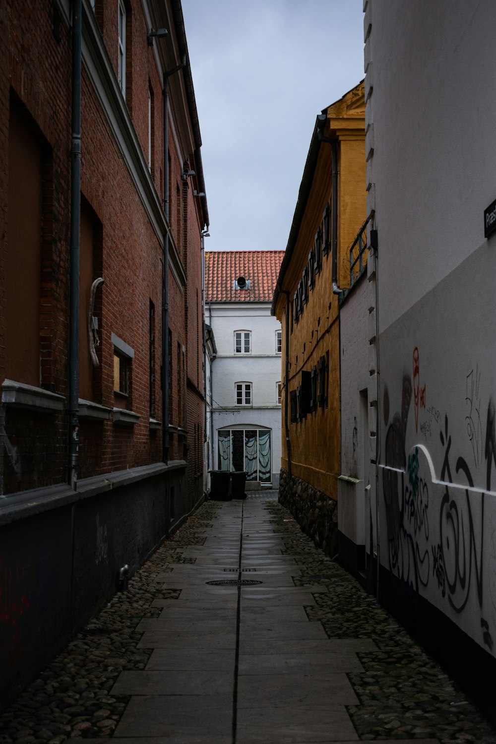 a narrow alley with graffiti on the walls