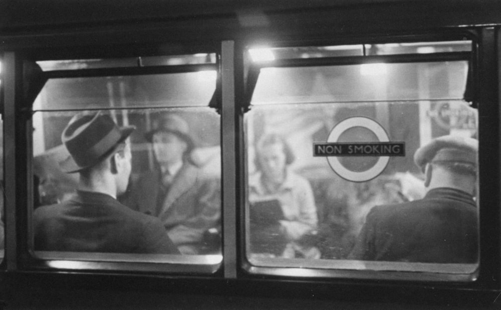 a black and white photo of people on a subway