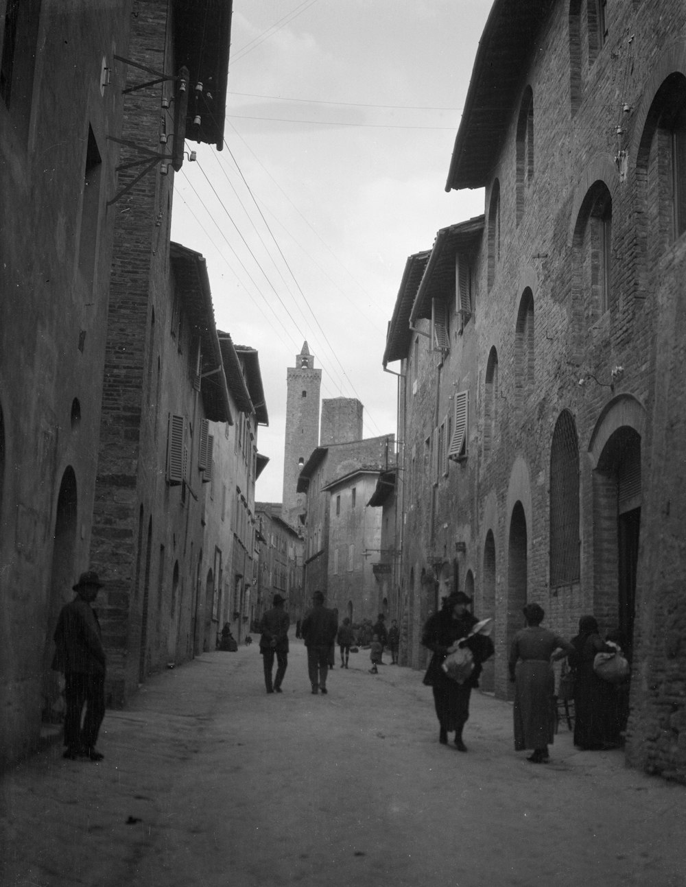 a group of people walking down a street next to tall buildings