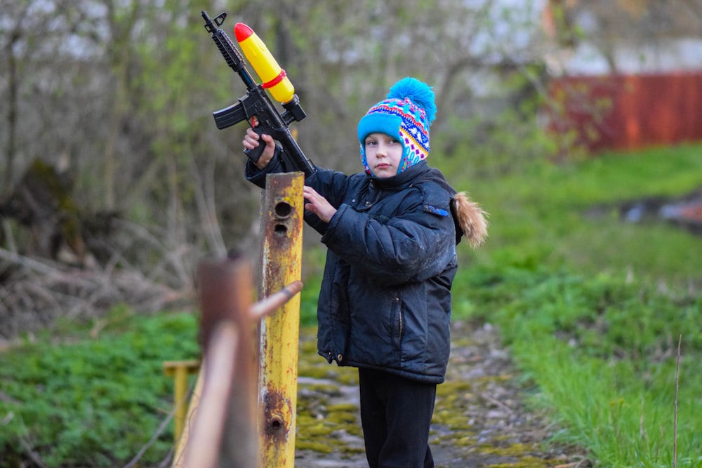 a young boy holding a toy gun on a bridge