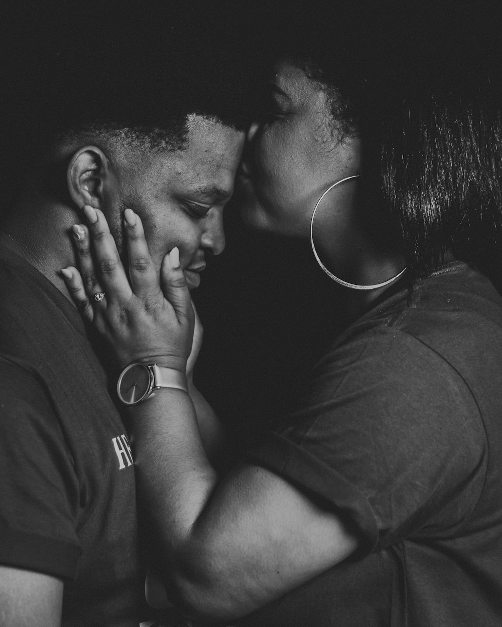 a black and white photo of a man kissing a woman