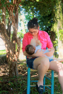 A serene outdoor scene of a mother nursing her baby surrounded by nature.