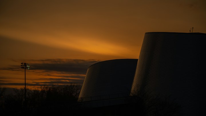 Nuclear cooling towers silhouetted against an orange sunset sky