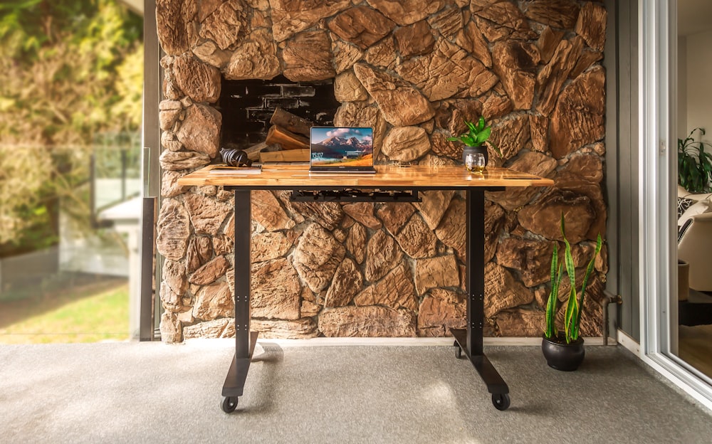 a table with a laptop on it in front of a stone wall