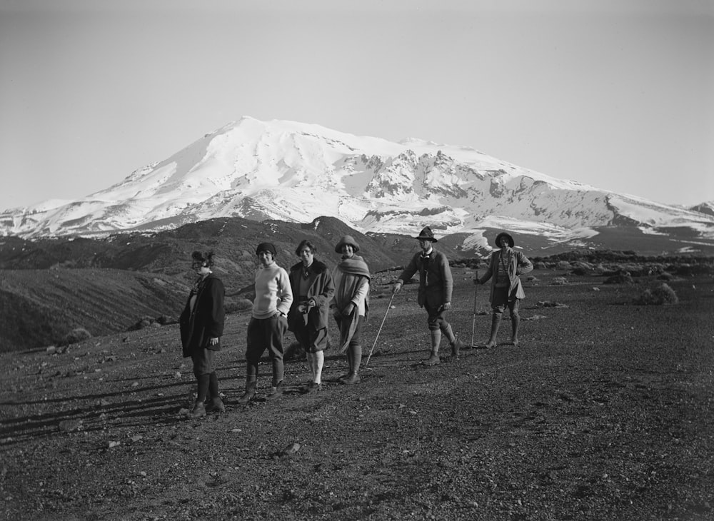 a group of people walking across a grass covered field