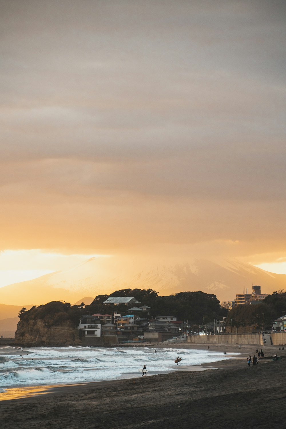 a group of people standing on top of a beach next to the ocean