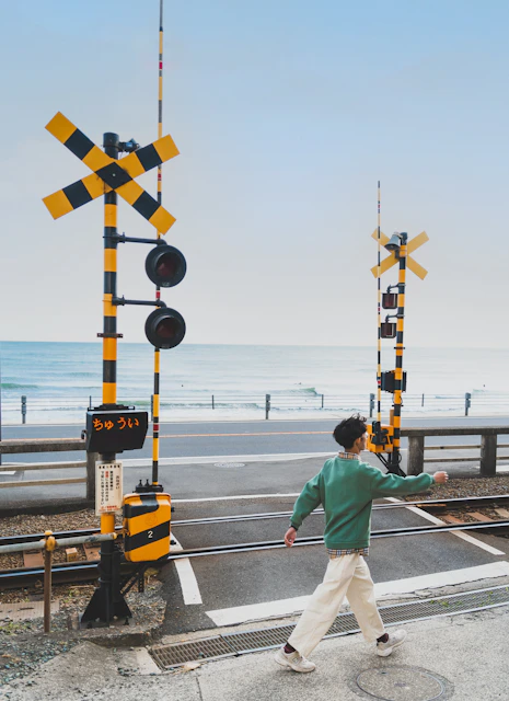 a man walking across a street next to railroad tracks