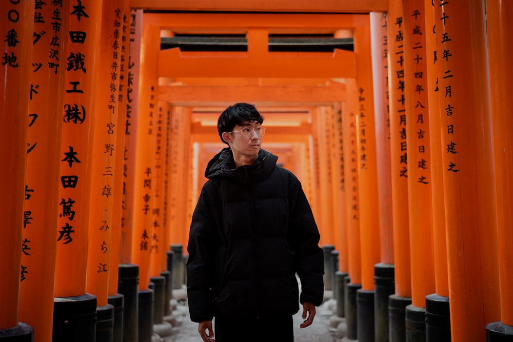 a man standing in front of a row of orange pillars