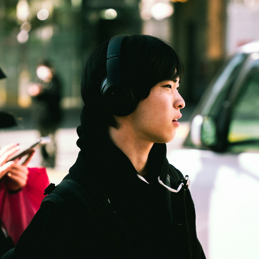 a man with headphones standing next to a car