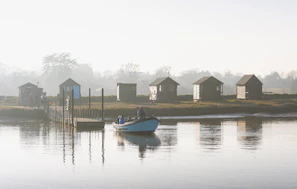 Cozy riverside resort cottages nestled along the water’s edge with morning mist rising.