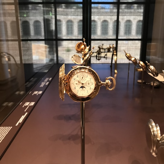 A display of vintage pocket watches with brass casings and delicate engravings, arranged on dark mahogany wood.