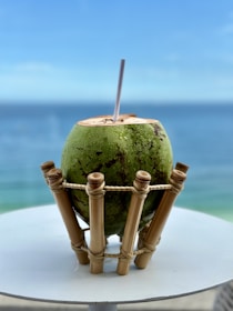 Close-up of a clear bottle filled with fresh coconut water surrounded by green coconut leaves.