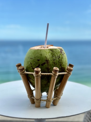 Refreshing coconut water served in a clear cup with tropical leaves in the background