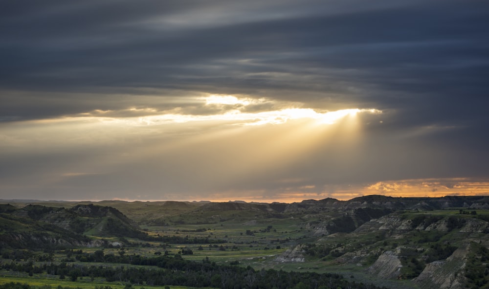 the sun shines through the clouds over a valley