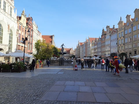 A traveler with a backpack looking at a map in a bustling European city square.