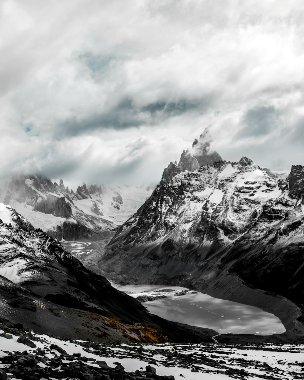 a snow covered mountain range with a lake in the foreground