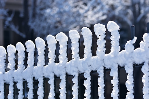 a fence covered in snow next to a building