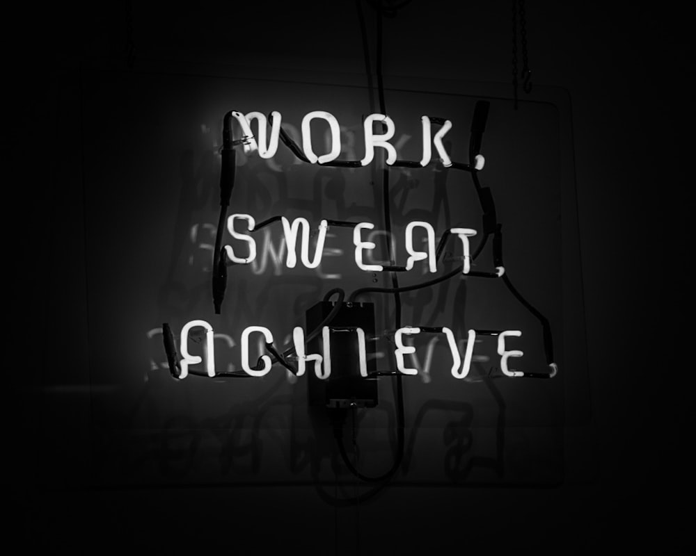 a neon sign that reads work, sweat, achieve