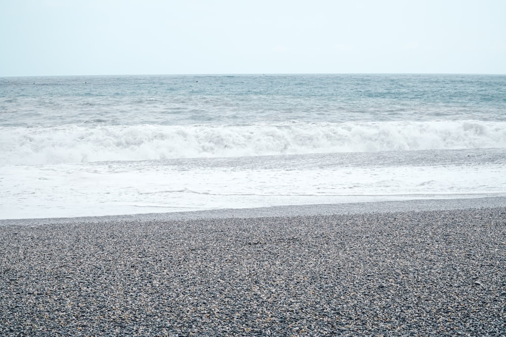 a person standing on a beach holding a surfboard