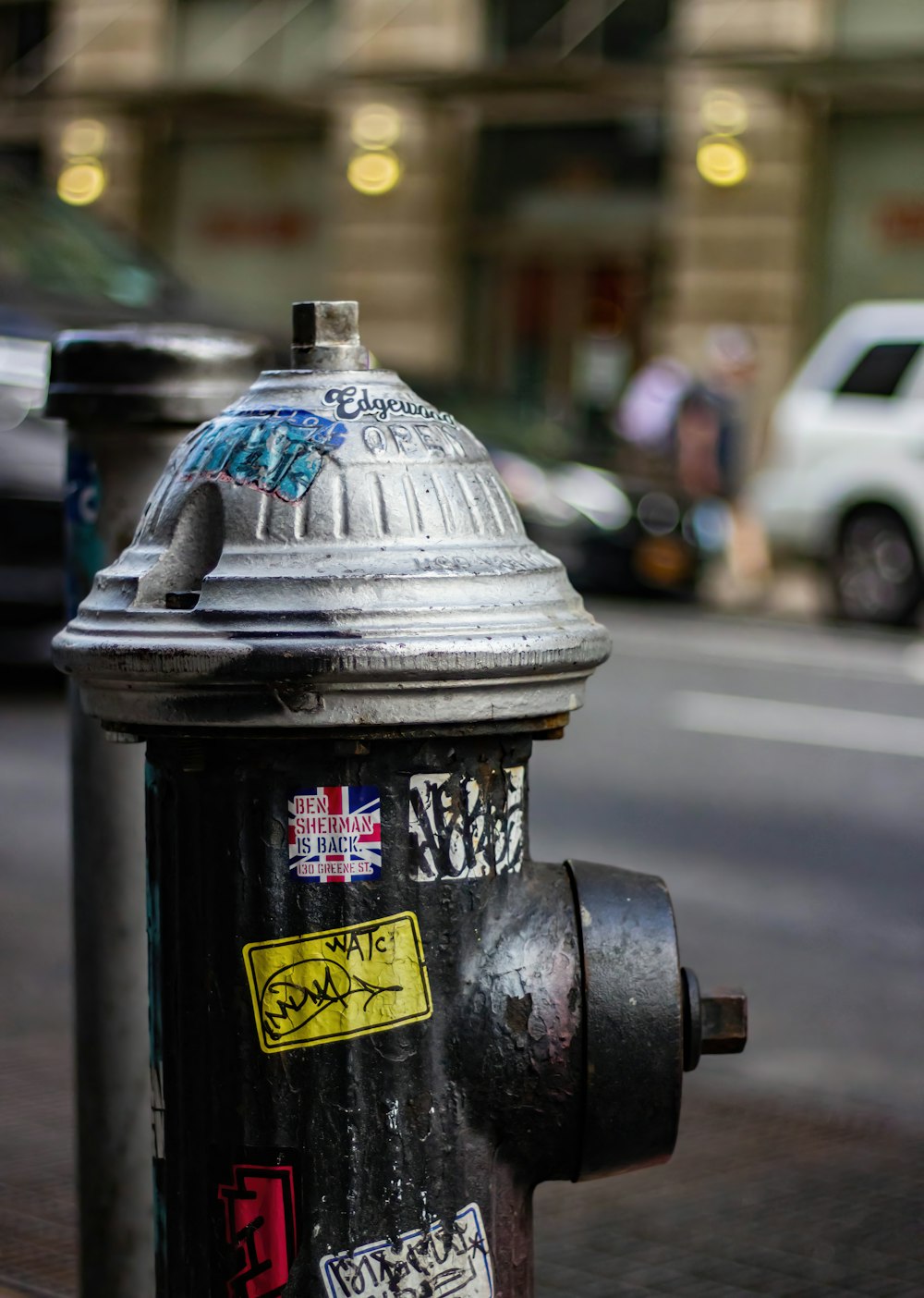 a black and silver fire hydrant with stickers on it
