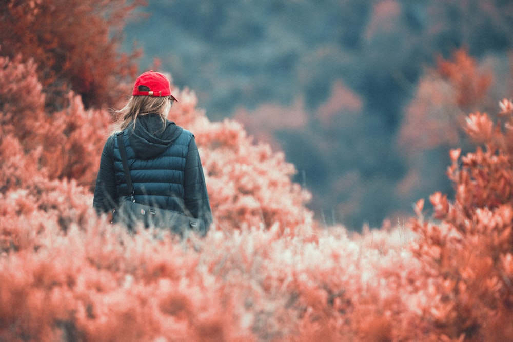 a woman in a red hat is walking through a field
