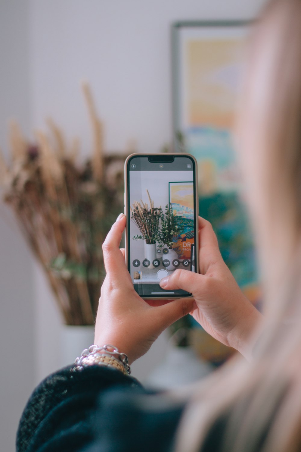 a woman taking a picture of a plant with her phone