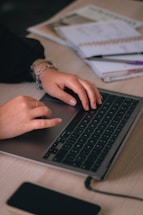A student sitting at a desk with a laptop and notebooks.
