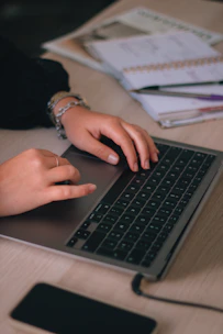 Close-up of hands typing on a keyboard with a smartphone and planner nearby, symbolizing organized remote work.