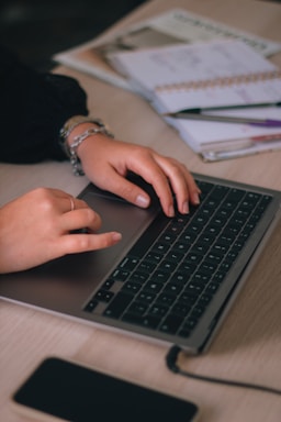 Hands typing on a laptop keyboard surrounded by organized receipts and notes.