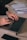 Close-up of hands typing on a laptop keyboard with a smartphone and notebook nearby.